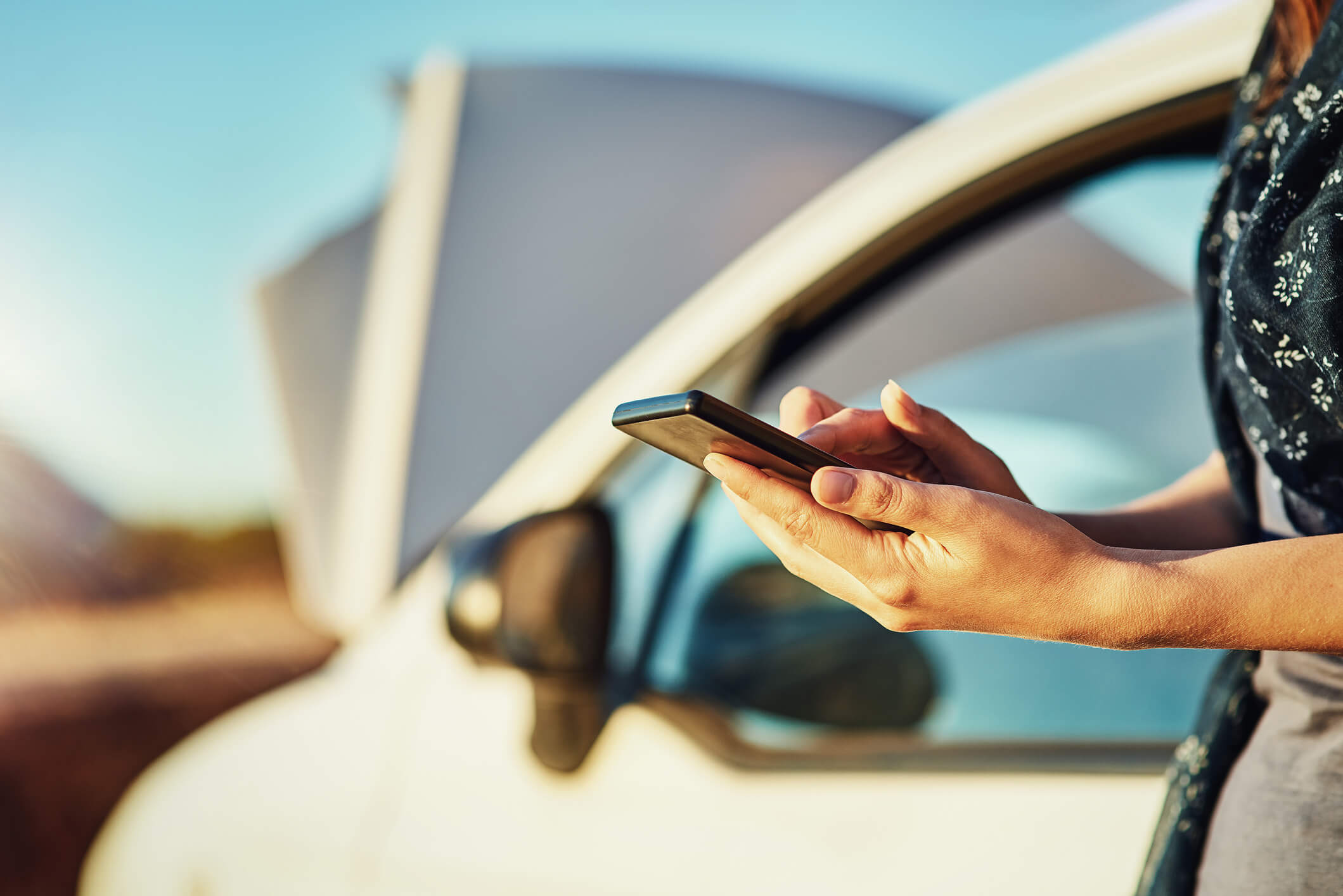 Frau am Telefon neben Auto mit Schaden
